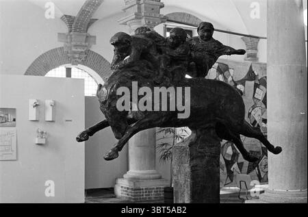 Ausstellung Skulpturen und Gemälde gekauft für die Gemeinde Haarlem Haarlem Niederlande, Whizgle News, Dutch Desk, Niederlande, 1950 - 2000 am 02-07-1966. Das Bild enthält diese Themen. Die Szene zeigt eine markante Skulptur, die in einem weitläufigen Innenraum sichtbar ist, der durch seine architektonischen Merkmale gekennzeichnet ist. Die Skulptur zeigt eine dynamische Gruppe von Figuren, wahrscheinlich Kinder, die auf einem stilisierten, muskulösen Pferd reiten. Die Figuren, die in einem dunklen metallischen Material gerendert sind, werden mit einem energetischen Bewegungsgefühl positioniert, als ob sie mitten im Galopp gefangen wären. Ihre Ausdrücke A Stockfoto