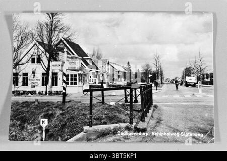 Print Badhoevedorp Kreuzung Schipholweg-Schoterweg Badhoevedorp Schipholweg., Whizgle News, Dutch Desk, Niederlande, 1950 - 2000. Diese Themen werden in der Abbildung angezeigt. Die Szene zeigt eine malerische, ländliche Gegend, die von einem charmanten Gebäude auf der linken Seite mit einem geneigten Dach und einer weißen Fassade mit dunklen Zierelementen gekennzeichnet ist. Das Gebäude scheint ein kleines Café oder gasthaus zu sein, mit großen Fenstern, die eine einladende Atmosphäre vermitteln. Um das Gebäude herum ist gut gepflegtes Grün zu sehen, das einen lebhaften Kontrast zu den gedämpften Farben der Architektur bietet. Im Vordergrund eine hölzerne Ba Stockfoto
