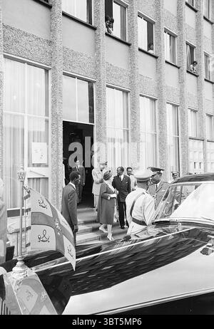 Königin Juliana Prinz Bernhard Prinzessin Beatrix Prinz Claus und Delegation bei Staatsbesuch in Äthiopien (Jan - Feb) Ethiopië, Whizgle News, Dutch Desk, Niederlande, 1950 - 2000 1969. Das Bild enthält diese Themen. In der Szene versammelt sich eine Gruppe gut gekleideter Individuen vor einem großen Gebäude, das durch eine Fassade gekennzeichnet ist, die strukturierten Stein mit großen, hellen Fenstern, die mit transparenten Vorhängen überzogen sind, kombiniert. Der Eingang ist deutlich sichtbar, mit mehreren Stufen, die hinauf führen. An der Vorderseite tritt eine Frau in hellem Anzug und passendem Hut anmutig die Treppe hinunter Stockfoto