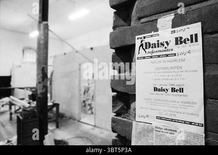 Übungsraum Daisy Bell Haarlem Niederlande, Whizgle News, Dutch Desk, Niederlande, 1950 - 2000 am 28.11.1994. Diese Themen werden in der Abbildung angezeigt. Die Szene fängt ein geräumiges, industrielles Ambiente ein, das sich durch sein unvollendetes Aussehen auszeichnet. Die Wände sind in gedämpftem Grau gestrichen und zeigen Abnutzungsflecken und Unregelmäßigkeiten, die auf ihre Geschichte hinweisen. Diese Umgebung wird von Leuchtstofflampen über dem Kopf beleuchtet, die ein helles, weißes Leuchten erzeugen, das das Gefühl der Offenheit verbessert und gleichzeitig Schatten in den Ecken freigibt. Auf einer Seite dient eine raue Ziegelmauer als Kulisse mit ihren strukturierten en Stockfoto