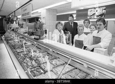 Verschiedene Aufnahmen Dirck III Zandvoort. Supermarkt Zandvoort Zandvoort, Whizgle News, Dutch Desk, Niederlande, 1950 - 2000 am 17-02-1989. Diese Themen werden in der Abbildung angezeigt. Die Szene zeigt ein geschäftiges Marktumfeld, insbesondere eine Fleischtheke, die eine Auswahl an Schnitten und Produkten präsentiert. Verschiedene Fleischsorten sind sorgfältig in einer Vitrine aus Glas angeordnet, mit Farben, die von tiefrotem bis hellem Rosa reichen, was auf Frische hinweist. Die Beleuchtung ist hell und gleichmäßig, verstärkt die lebendigen Fleischtöne und schafft eine einladende Atmosphäre. Im Vordergrund steht eine Gruppe von sechs Individuen i Stockfoto