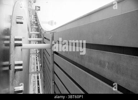 Erhöhte Zufahrtsstraßen nach Schiphol Schiphol, Whizgle News, Dutch Desk, Niederlande, 1950 - 2000 am 31-03-1993. Dies sind die Elemente im Bild. Die Szene präsentiert eine markante urbane Landschaft, die sich durch ein starkes Geometriegefühl und starke Kontraste auszeichnet. Eine breite Betonplattform dominiert den Vorderboden, deren Oberfläche glatt und dennoch strukturiert ist und Licht und Schatten reflektiert. Die eckigen Kanten der Plattform führen das Auge zu einer Reihe vertikaler Säulen, die in steilen Linien stehen und strukturellen Halt bieten. Der Hintergrund zeigt eine weitläufige Autobahn oder Straße, wahrscheinlich erhöht, i Stockfoto