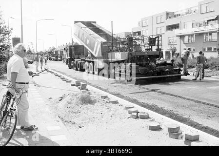 New Construction Res Nova Square New Construction Heemstede Res Novaplein The Netherlands, Whizgle News, Dutch Desk, Niederlande, 1950 - 2000 am 23-08-1989. Diese Themen sind in der Abbildung dargestellt. Die Szene zeigt eine geschäftige Stadtstraße bei hellem Tageslicht, die mit Bauarbeiten oder Bauarbeiten gefüllt ist. Ein großer, schwerer Lkw sitzt im Vordergrund, dessen Bett angehoben ist, um Material freizulegen, das sich auf der Straße abgesetzt hat. Der Lkw ist in einem auffälligen Farbschema mit auffälligen Mustern lackiert und trägt so zum industriellen Flair der Szene bei. Um den Truck herum, mehrere Arbeiter A Stockfoto
