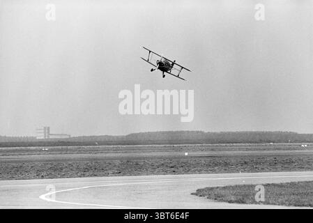 Martinair Lelystad: Stunt Fliegen Udo kauft an der Steuerung People Flugzeuge Lelystad, Whizgle News, Dutch Desk, Niederlande, 1950 - 2000 am 04-08-1981. Dies sind die Themen im Bild. Die Szene fängt einen Moment in der Luftfahrt ein und präsentiert einen Vintage-Doppeldecker mitten im Flug, der ein scharfes Manöver über einer weitläufigen Landebahn durchführt. Das Flugzeug, das sich durch seine Doppelflügel und ein klassisches Design auszeichnet, ist dramatisch abgewinkelt, während es sich zur Seite neigt, was seine Agilität zum Ausdruck bringt. Der Hintergrund zeigt eine breite, flache Landebahn, die sich bis in die Distanz erstreckt und von einer grasbewachsenen Weite begrenzt wird, die in ein wenig Licht übergeht Stockfoto