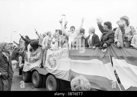 Fulmars Champion Tour IJmuiden Football IJmuiden Niederlande, Whizgle News, Dutch Desk, Niederlande, 1950 - 2000 am 27.05.1984. Die Abbildung zeigt diese Themen. Die Szene ist lebendig und voller Energie, in der eine Gruppe von Menschen auf einem großen Fahrzeug, wahrscheinlich einem Tieflader, feiert. Die Atmosphäre ist festlich, geprägt von einem Gefühl der Freude und Kameradschaft unter den Menschen. Die Leute tragen eine Mischung aus legeren Kleidern, mit einigen Sportjacken und Pullover, die auf einen bewölkten oder kühleren Tag hinweisen. Ihre Ausdrucksformen sind animiert; viele lächeln weit, andere dagegen Stockfoto