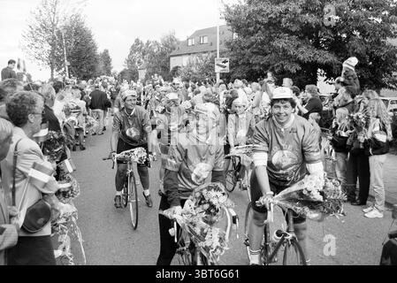 Ankunft der Radfahrer Vijfhuizen Vijfhuizen, Whizgle News, Dutch Desk, Niederlande, 1950 - 2000 am 07-09-1996. Dies sind die Elemente im Bild. Die Szene fängt einen lebendigen Moment in einem Radsport-Event voller Spannung und Kameradschaft ein. Eine Gruppe von Radfahrerinnen, die in bunten Trikots mit markanten Mustern verziert sind, fahren mit ihren Fahrrädern eine Straße entlang, die von begeisterten Zuschauern gesäumt ist. Jeder Radfahrer trägt eine Mütze, und sie sind mit Blumenkränzen verziert, die eine feierliche Atmosphäre widerspiegeln. Die umliegende Menge ist vielfältig, besteht aus Männern, Frauen und Kindern, viele o Stockfoto