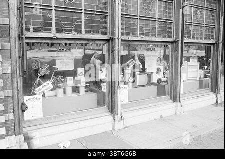 Extern. Schaufenster Stadtpreise Brinkmann Exterior, Whizgle News, Dutch Desk, Niederlande, 1950 - 2000 am 19-11-1973. Diese Themen sind in der Abbildung dargestellt. Die Szene verfügt über eine Reihe von großen Anzeigefenstern, die eine Reihe von Gegenständen in einem Geschäft freigeben. Die Architektur des Storefront zeigt eine Kombination aus klassischen und Vintage-Designelementen, mit kunstvollen Glasmustern und Holzrahmen, die Charakter verleihen. Im Inneren sind verschiedene Objekte kunstvoll auf Regalen und Theken angeordnet. Es gibt eine Mischung aus Vintage-Möbeln, Küchenutensilien und dekorativen Gegenständen. Ein kleiner Tisch zeigt Topfpflanzen Stockfoto