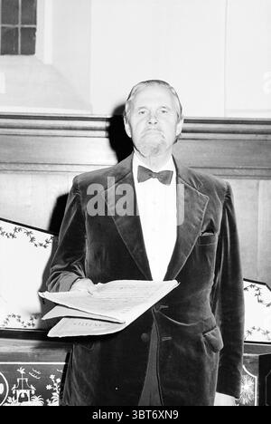 Bakenesserkerk Alfred Geller Personen singen und Musik, Whizgle News, Dutch Desk, Niederlande, 1950 - 2000 am 11-01-1979. Dies sind die Elemente im Bild. In der Szene steht ein Mann selbstbewusst vor einer hölzernen Kulisse, die einen Vintage-Charme ausstrahlt. Er trägt ein formelles Outfit mit einer klassischen Samtjacke in einem satten dunklen Farbton, der einen schönen Kontrast zum knackigen weiß seines Hemdes bildet. Eine Schleife, die ordentlich gebunden und perfekt positioniert ist, sorgt für Raffinesse. Sein Ausdruck ist ernst und doch bezeichnend, mit einem leichten Hauch von würde, was auf einen wichtigen Moment hindeutet. Er ist hier Stockfoto