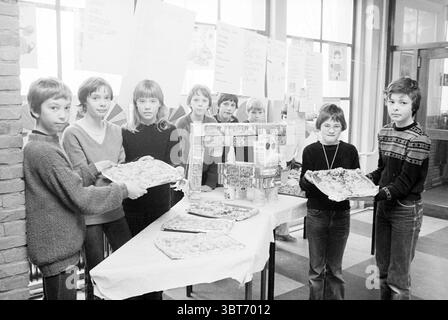 Schüler machen kalte Gerichte St. Margrietschool Beverwijk Kochschulen Beverwijk Niederlande, Whizgle News, Dutch Desk, Niederlande, 1950 - 2000 am 25-02-1981. Diese Themen sind in der Abbildung dargestellt. In einem hellen, geräumigen Innenbereich steht eine Gruppe von Kindern stolz und präsentiert eine Vielzahl von Speisen auf einem langen Tisch. Die Wände sind mit Plakaten geschmückt, die auf eine Gemeinde oder ein Schulevent hinweisen, bei dem jedes Kind mit Begeisterung teilnimmt. Die Gruppe besteht aus mehreren Jungen und Mädchen, die in einer Mischung aus Pullover und lässiger Kleidung gekleidet sind und eine warme, freundliche Atmosphäre widerspiegeln Stockfoto