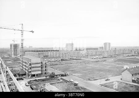 Übersicht über die Gebäude des Europäischen Viertels, Whizgle News, Dutch Desk, Niederlande, 1950 - 2000 am 18-11-1964. Das Bild enthält diese Themen. Die Szene zeigt eine riesige urbane Landschaft, in der vor allem eine Reihe moderner Gebäude im Bau sind. Die Architektur wirkt utilitaristisch, mit einer Mischung aus mittleren bis hohen Gebäuden, die sich zusammengeschlossen haben, was auf ein sich entwickelndes Wohngebiet hinweist. Im Vordergrund ragen mehrere Kräne, deren Höhe sich von den unteren Gebäuden abhebt. Die Landschaft ist durch gedämpfte Töne, vorwiegend Grautöne, Kreatöne geprägt Stockfoto