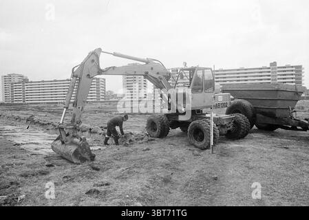 Bau des Europaweg-Sportplatzes. Arbeiten Sie Haarlem Europaweg the Netherlands, Whizgle News, Dutch Desk, Niederlande, 1950 - 2000 am 03-02-1971. Dies sind die Themen im Bild. Die Szene zeigt eine industrielle Arbeitsstätte, die durch eine gedämpfte Farbpalette gekennzeichnet ist, die von Grautönen dominiert wird, die den bewölkten Himmel und die Umgebung reflektieren. Im Vordergrund steht ein großes Stück schwerer Maschinen, wahrscheinlich ein Bagger. Der Arm fährt nach außen und greift einen Löffel, der in die Erde zu graben scheint. Ein Arbeiter in dunkler Kleidung befindet sich in der Nähe der Maschine. Er Stockfoto