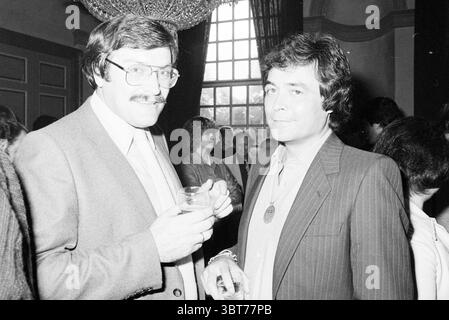 Empfang Mary Servaes (Singer ohne Namen) Personal Sing- und Musikempfänge, Whizgle News, Dutch Desk, Niederlande, 1950 - 2000 am 27-09-1979. Das Bild enthält diese Themen. In einem eleganten Innenbereich stehen zwei Männer an prominenter Stelle in einem lebhaften Treffen. Die Kulisse bietet reiche, dunkle Vorhänge, die große Fenster umrahmen, die weiches Umgebungslicht durchdringen lassen und eine warme und einladende Atmosphäre schaffen. Ein Mann trägt einen hellgrauen Anzug, hat einen dicken Schnurrbart und eine Sportbrille. Er hält ein Glas mit einem hellen Getränk und strahlt eine selbstbewusste Luft aus, während er Gespräche führt Stockfoto