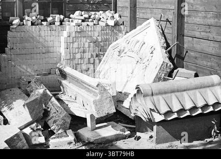Fassadenstein der Papierfabrik Gelder Van Gelder & Zonen Velsen, Whizgle News, Dutch Desk, Niederlande, 1950 - 2000 am 16.09.1971. Das Bild enthält diese Themen. In dieser Szene gibt es eine Sammlung von verschiedenen Baumaterialien und architektonischen Überresten, die etwas chaotisch angeordnet sind. Ein Stapel von einheitlichen Blöcken, wahrscheinlich Ziegeln, wird ordentlich im Hintergrund positioniert, wodurch ein Gefühl der Ordnung in der Unordnung entsteht. Im Vordergrund ist eine Reihe von Steinfragmenten ausgestreut, darunter ein großes Stück mit komplizierten Schnitzereien, möglicherweise von einer alten Fassade. Die Textur des ston Stockfoto
