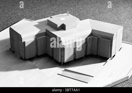 Modell in verschiedenen Sonnenlicht-Auftragnehmern ME N-H Model, Whizgle News, Dutch Desk, Niederlande, 1950 - 2000 am 25-11-1981. Diese Themen werden in der Abbildung angezeigt. Die Szene zeigt ein maßstabsgetreues Modell einer zeitgenössischen architektonischen Struktur, die auf einer flachen Oberfläche präsentiert wird. Das Modell ist aus hellem Holz gefertigt und weist eine glatte Oberfläche auf, die die natürliche Körnung und Textur des Materials unterstreicht. Das Design des Gebäudes ist eckig und geometrisch, gekennzeichnet durch eine Reihe ineinander greifender Volumen, die eine dynamische Silhouette erzeugen. Verschiedene Abschnitte weisen unterschiedliche Höhen und Tiefen auf, Stockfoto