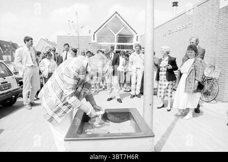 Eröffnung von 5 Schulen Hoofddorp Eröffnungen Inbetriebnahme Schulen Hoofddorp Niederlande, Whizgle News, Dutch Desk, Niederlande, 1950 - 2000 am 01-06-1988. Das Bild enthält diese Themen. In einer belebten Outdoor-Szene versammelt sich eine vielfältige Gruppe von Menschen auf einem Platz in der Nähe eines modernen Gebäudes, das von großen Glasfenstern und einer markanten Ziegelfassade geprägt ist. Die Menge, die aus Männern und Frauen in verschiedenen Kleidungsstücken besteht – von Anzügen und Krawatten bis hin zu lässigen Kleidern –, zeigt eine Vielzahl von Farben, wobei die Gesamtpalette sich in neutralen Tönen mit gelegentlichen Farbtupfern orientiert. Im Vordergrund Stockfoto