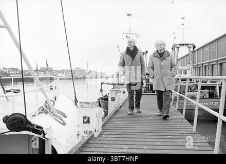 Vater und Sohn Van Woensel erfanden Garnelenschälmaschinen-Erfindungen, Whizgle News, Dutch Desk, Niederlande, 1950 - 2000 am 17. 12. 1978. Diese Themen sind in der Abbildung dargestellt. Die Szene fängt eine monochrome Hafenumgebung ein, die ein Gefühl von Nostalgie und Ruhe weckt. Zwei Personen gehen an einem hölzernen Dock entlang, ihre Figuren stehen vor dem Hintergrund von vertäuten Booten. Die erste Person zeigt ein ausgeprägtes Verhalten mit einem hellen Mantel, während die zweite mit weißem Haar ein dunkleres Fell trägt. Ihre entspannte Haltung vermittelt Komfort und Vertrautheit mit jedem o Stockfoto