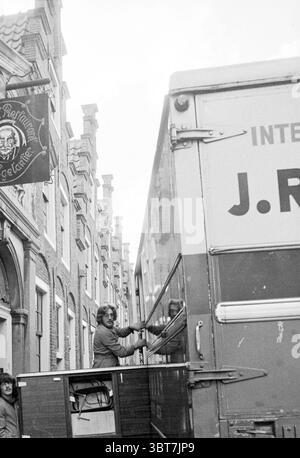 Clearing Café Cultural Center de Egelantier (fahrender Van auf der Straße) Haarlem Groot Heiligland Niederlande, Whizgle News, Dutch Desk, Niederlande, 1950 - 2000 am 20-11-1978. Das Bild enthält diese Themen. In einer lebhaften urbanen Szene bietet eine enge Straße eine Mischung aus historischen Gebäuden mit unverwechselbarer Architektur. Die Fassaden zeigen eine Kombination aus Ziegel und Stein, mit hohen, schmalen Fenstern und verzierten Details. Auf der einen Seite gibt es ein Schild, das auf ein nahegelegenes Etablissement hinweist, möglicherweise auf ein Pub oder Restaurant, was der Umgebung einen Hauch von Charakter verleiht. An der Spitze, ein großes Stockfoto