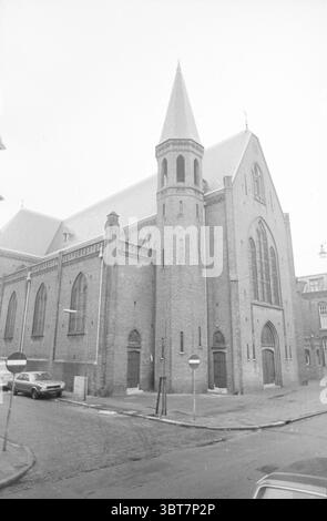 Außenfassade römisch-katholische Kirche Elisabeth and Barbara Haarlem-Noord Haarlem Paul Krugerstraat 43 Niederlande, Whizgle News, Dutch Desk, Niederlande, 1950 - 2000 am 20-02-1978. Dies sind die Themen im Bild. Die Szene zeigt ein großes, imposantes Gebäude, das wie eine historische Kirche oder Kathedrale aussieht. Das Äußere besteht überwiegend aus rötlich-braunem Ziegelstein, was der Struktur ein solides und robustes Aussehen verleiht. Sein architektonischer Stil umfasst Spitzbögen und große Fenster mit komplizierten Mauerwerken um sie herum, was auf einen gotischen Einfluss hindeutet. An einem Ende von Stockfoto