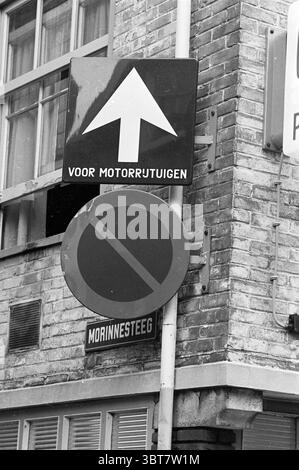 Verkehrsschilder für Einbahnverkehr und Parken verboten Morinnesteeg Ecke Smedestraat Haarlem Smedestraat Niederlande., Whizgle News, Dutch Desk, Niederlande, 1950 - 2000. Dies sind die Elemente im Bild. Die Szene zeigt eine Kombination von Straßenschildern, die an einem vertikalen Pfosten angebracht sind und an einer Ziegelwand angebracht sind, die eine raue, strukturierte Oberfläche zeigt. Das obere Zeichen zeigt einen fettgedruckten Pfeil, der nach oben zeigt und die Richtung angibt. Sein Farbschema umfasst einen hellen Hintergrund, wahrscheinlich weiß, der sich in einem scharfen Kontrast zum schwarzen Pfeil bildet, was Klarheit in der Anleitung vermittelt. Darunter noch ein weiterer Stockfoto