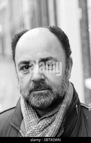 Herr Sevil Gemeindeentwickler Frans Halsbuurt Ausländer Nachbarschaften Gemeindezentren örtliche Geschäfte Trainingszentren, Whizgle News, Dutch Desk, Niederlande, 1950 - 2000 am 24-11-1983. Die Abbildung zeigt diese Themen. In der Szene steht ein Mann mittleren Alters in einer leichten Nahaufnahme und strahlt eine nachdenkliche, aber dennoch zugängliche Präsenz aus. Sein Haar ist hauptsächlich Salz-und-Pfeffer, mit einer auffälligen Glatze oben. Ein gepflegter Bart umrahmt sein Gesicht, verleiht seinem Ausdruck Tiefe und betont seine Gesichtszüge. Er trägt einen dunklen Mantel, der warm und funktional wirkt. Umwickelt um seinen nec Stockfoto