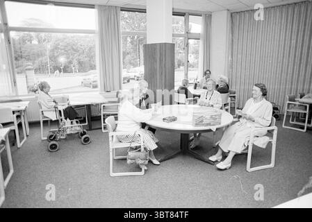 Konversationsraum Jacob in de Hout, Whizgle News, Dutch Desk, Niederlande, 1950 - 2000 am 17.09.1992. Das Bild enthält diese Themen. In einem geräumigen Raum mit großen Fenstern, die natürliches Licht einströmen lassen, versammeln sich eine Gruppe älterer Personen um einen runden Tisch. Das Ambiente strahlt eine ruhige und einladende Atmosphäre aus, mit einer sanften Farbpalette, die überwiegend in gedämpften Grau-, Beige- und Pastelltönen gehalten ist. Der Boden ist mit einem dezenten grauen Teppichboden ausgelegt, der die ruhige Umgebung unterstreicht. Am Tisch sind sechs Personen an einem temperamentvollen Spiel oder einer Aktivität beteiligt, ihre Ausdrücke sind lebendig, Stockfoto