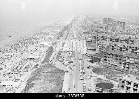 By Zandvoort By Zandvoort, Whizgle News, Dutch Desk, Niederlande, 1950 - 2000 am 07-06-1965. Das Bild enthält diese Themen. Die Szene fängt ein lebhaftes Küstengebiet ein. Auf der linken Seite erstreckt sich ein Sandstrand entlang der Küste, der von zahlreichen Sonnenanbetern, leuchtenden Sonnenschirmen und farbenfrohen Handtüchern gesäumt ist. Die Menschen genießen ihre Zeit, einige faulenzen, während andere aktiv Strandspiele spielen, schwimmen oder am Ufer entlang spazieren gehen. Im Vordergrund verläuft parallel zum Strand eine breite, gepflasterte Straße, gesäumt von einer Mischung aus geparkten Autos in verschiedenen Farbtönen, von klassischen Weißtönen Stockfoto