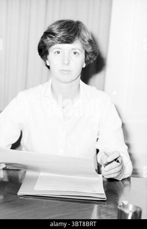 Installation von 2 neuen Ratsmitgliedern in Bloemendaal + einige Porträts, einschließlich neuer Ratsmitglied der Gemeinde Bloemendaal Bloemendaal, Whizgle News, Dutch Desk, Niederlande, 1950 - 2000 am 02-01-1980. Dies sind die Themen im Bild. Die Szene zeigt eine junge Frau, die an einem Holztisch sitzt. Sie hat eine kurze Frisur, die ordentlich gepflegt wirkt, was ihre Gesichtszüge unterstreicht. Die Frau trägt ein helles Hemd mit Button-Down-Hemd, das ihrem Aussehen einen Hauch von Einfachheit verleiht. Sie ist fokussiert und blickt direkt auf den Betrachter mit einem ernsten Ausdruck, der Entschlossenheit oder Concen vermittelt Stockfoto