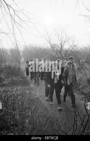 Beach Walk Haarlems Dagblad Haarlems Dagblad etc. Und IJmuider Courant and Koeri Walking 31-07-1980, Whizgle News, Dutch Desk, Niederlande, 1950 - 2000 am 15-02-1981. Dies sind die Elemente im Bild. Die Szene zeigt eine Gruppe von Individuen, die auf einem schmalen Pfad durch eine trübe Landschaft spazieren. Die Atmosphäre ist erfüllt von einem Gefühl der Ruhe und Einsicht, verstärkt durch das weiche, gedämpfte Licht, das durch den Nebel filtert. Im Vordergrund umrahmt ein Gewirr aus Ästen und Unterholz den Weg und weist auf die natürliche Umgebung der Gruppe hin. Die Teilnehmer Stockfoto