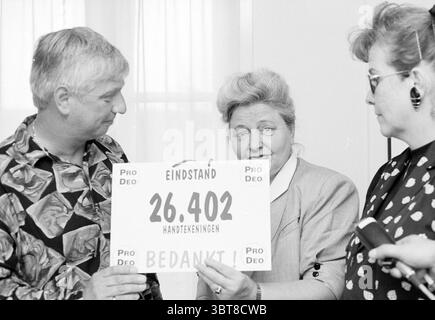 Unterschriftenübergabe durch das Deo an Bürgermeister Schultz Haarlem, Niederlande, Whizgle News, Dutch Desk, Niederlande, 1950 - 2000 am 24.05.1993. Dies sind die Themen im Bild. In der Szene werden drei Individuen zusammen positioniert, deren Ausdruck eine Mischung von Emotionen vermittelt. Links steht ein Mann mittleren Alters, der ein gemustertes Hemd mit auffälligen Farben trägt, das durch seine Wirbel und Umrisse einen lebendigen Look schafft. Er hat helles Haar und sieht leicht zur Seite, was ein engagiertes Verhalten widerspiegelt. In der Mitte dominiert eine Frau mit ihrem voluminösen, gestylten Haar die Aufmerksamkeit Stockfoto