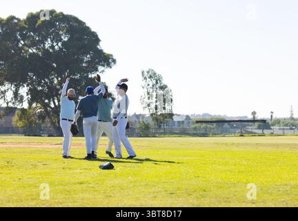 Männliche Baseballkameraden feiern mit Handschuhen und Kopierraum das Spiel auf dem Feld um Zaun Stockfoto