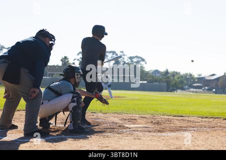 Verschiedene Baseballspieler schwingen Schläger und fangen Ball mit Handschuh und Helm auf der Heimteller Stockfoto