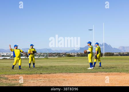 Verschiedene männliche Mannschaftskameraden in gelb-blauen Uniformen stehen auf dem Feld und halten Handschuhe unter Rugbypfosten Stockfoto
