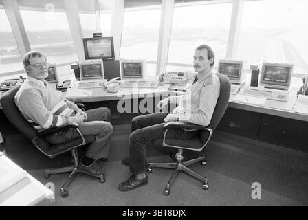 Neue Ausrüstung IJmuiden Port Service Ports IJmuiden Niederlande, Whizgle News, Dutch Desk, Niederlande, 1950 - 2000 am 24-02-1987. Diese Themen werden in der Abbildung angezeigt. Die Szene zeigt zwei Personen, die in einem Kontrollraum sitzen und sich durch eine Reihe technologischer Geräte auszeichnen. Der Raum ist mit mehreren Computermonitoren gefüllt, von denen jeder verschiedene Messwerte und Daten anzeigt, was auf eine High-Tech-Umgebung hindeutet, die wahrscheinlich mit der Flugsicherung oder einer ähnlichen Umgebung zusammenhängt. Die Personen sind nebeneinander positioniert, beide zeigen nach vorne. Die erste Person links hat eine Brille und einen Bart, dr. Stockfoto