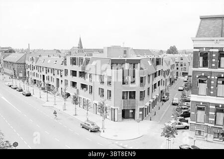 Außenhäuser im Hotel altes Gebäude in Spaarnestad Außenhäuser und Hausbau, Whizgle News, Dutch Desk, Niederlande, 1950 - 2000 am 19-08-1981. Dies sind die Elemente im Bild. Die Szene fängt eine urbane Umgebung ein, die von moderner Architektur geprägt ist. Eine Gruppe von mehrstöckigen Gebäuden zeigt eine Mischung aus Ziegelsteinen und zeitgenössischen Designelementen mit großen Fenstern, die die Umgebung widerspiegeln. Die Farbpalette ist monochromatisch, dominiert von unterschiedlichen Grautönen, was dem Bereich ein starkes, aber harmonisches Aussehen verleiht. Links verläuft eine breite, von Bäumen gesäumte Straße Stockfoto