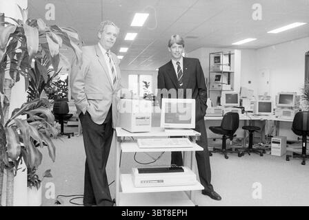 Mr. Compaan und Lobken K.N. Badhoevedorp Computer People Companies Badhoevedorp, Whizgle News, Dutch Desk, Niederlande, 1950 - 2000 auf 30-05-1989. Das Bild enthält diese Themen. Die Szene spielt in einer geräumigen Büroumgebung, die durch eine helle und offene Atmosphäre gekennzeichnet ist. Zu den vorherrschenden Farben gehören weiß- und Grautöne, die zu einem sauberen und professionellen Look beitragen. Im Vordergrund stehen zwei Männer neben einem Arbeitsplatz. Ein Mann trägt einen hellgrauen Anzug mit gemusterter Krawatte, der Autorität und Professionalität vermittelt. Er hat eine selbstbewusste Haltung, die Arme sind entspannt Stockfoto