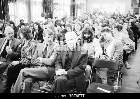 Manager Lescrauwaet am Mendel College Roman Catholic Church, Whizgle News, Dutch Desk, Niederlande, 1950 - 2000 am 22-03-1984. Dies sind die Elemente im Bild. Die Szene zeigt eine große Versammlung von Einzelpersonen, die in Reihen sitzen und eine Atmosphäre der Vorfreude und des Engagements schaffen. Der Raum ist gefüllt mit einer vielfältigen Gruppe von Menschen, überwiegend jungen Erwachsenen und Jugendlichen, was eine lebendige, Jugendliche Umgebung anzeigt. Im Vordergrund steht eine kleine Gruppe von Männern, die in formeller Kleidung gekleidet sind. Ein Mann trägt einen Anzug und eine Krawatte zu einem hellen Hemd, während ein anderer ein legeres trägt Stockfoto