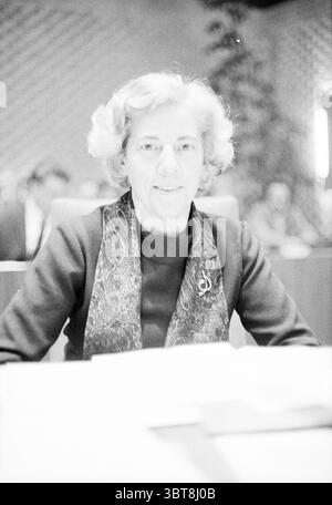 Beverwijk council leitet den Beverwijk gemeinderat, Whizgle News, Dutch Desk, Niederlande, 1950 - 2000 am 27-01-1972. Das Bild enthält diese Themen. In einer gut beleuchteten Umgebung sitzt eine Frau selbstbewusst an einem Schreibtisch und strahlt einen Hauch von Professionalität aus. Sie hat einen hellen Teint und ein warmes Lächeln, eingerahmt von weichen, welligen, hellen Haaren, die direkt über ihre Schultern fallen. Ihre Kleidung hat ein dunkles Oberteil, das einen deutlichen Kontrast zu einem gemusterten Schal bildet, der elegant um ihren Hals gelegt ist und komplizierte Designs und reichhaltige Texturen aufweist. Im Hintergrund gibt es einen Hinweis auf eine geschäftige Umgebung Stockfoto