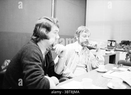 Porträt Herr Heus Direktor des Haarlemmermeer Lyceum mit Kollegen ab Lohuis (links) Haarlemmermeer, Whizgle News, Dutch Desk, Niederlande, 1950 - 2000 am 27.09.1979. Diese Themen sind in der Abbildung dargestellt. Die Szene zeigt zwei Männer, die an einem Holztisch in einem bescheidenen Innenraum sitzen. Sie sind in Gesprächen verwickelt, jeder trägt einen nachdenklichen Ausdruck. Der Mann auf der linken Seite hat einen Vollbart und zottelige Haare, lässig in einen dunklen Pullover gekleidet. Seine Hand liegt nahe seinem Kinn, was auf tiefe Besinnung hindeutet. Zu seiner Rechten trägt der zweite Mann einen helleren Bart und ein kurzes Haar, das mit einem Light-C verziert ist Stockfoto