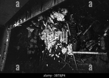Bervage norwegischer Tanker Knudsen Wijsmuller, Whizgle News, Dutch Desk, Niederlande, 1950 - 2000 am 27-04-1966. Dies sind die Elemente im Bild. Die Szene zeigt eine chaotische Ansammlung von Trümmern, die über eine schwach beleuchtete Oberfläche verstreut sind. Verschiedene Arten von Materialien sind verstreut, darunter zerknittertes Papier, verstreute Stoffe und Holzbalken, wodurch ein Gefühl der Störung entsteht. Die Farben sind überwiegend gedämpft, wobei Grau- und Schwarztöne vorherrschen, die gelegentlich durch das weiß des Papiers und leichte Anklänge dunklerer Farben aus dem Holz verstärkt werden. Die Beleuchtung ist schwach und Schatten dominieren, die wirken Stockfoto