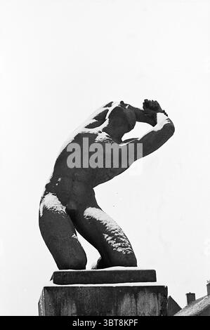 Resistance Monument Lisse Borden Lisse Oranjelaan, Whizgle News, Dutch Desk, Niederlande, 1950 - 2000 am 19-02-1964. Das Bild enthält diese Themen. Die Szene zeigt eine auffällige, monochrome Statue, die ihre dramatischen Konturen und Texturen betont. Die Figur wird in einer gehockerten Position gestellt, was auf ein Gefühl von Spannung und Selbstbetrachtung hindeutet. Das Motiv erscheint muskulös und weist definierte anatomische Merkmale auf, die sowohl Stärke als auch Verletzlichkeit vermitteln. Die Oberfläche der Skulptur ist strukturiert, mit hellen Schatten, die die Kurven und Winkel des Körpers betonen. Das Spiel des Lichts Stockfoto