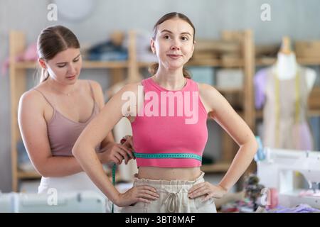 Junge Schneiderin nimmt Körpermaße von erwachsenen Frauen Stockfoto
