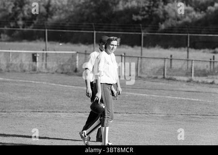 Terrace Birds - Sparks, Whizgle News, Dutch Desk, Niederlande, 1950 - 2000 am 04-08-1995. Dies sind die Themen im Bild. In einer sonnigen Umgebung im Freien werden zwei junge Menschen gefangen, die über ein grasbewachsenes Feld laufen. Die Landschaft ist gespickt mit hohem Gras und Sträuchern im Hintergrund, eingerahmt von einem Zaun, der die Gegend umgibt. Eine Person trägt ein helles, gestreiftes Hemd, das eine entspannte, sportliche Atmosphäre unterstreicht, ergänzt durch eine dunkle Hose, die sich an den Knöcheln leicht verjüngt. Sie haben eine selbstbewusste Haltung und halten beiläufig einen Baseballhandschuh in einer Hand. Ihr Ausdruck vermittelt sich Stockfoto