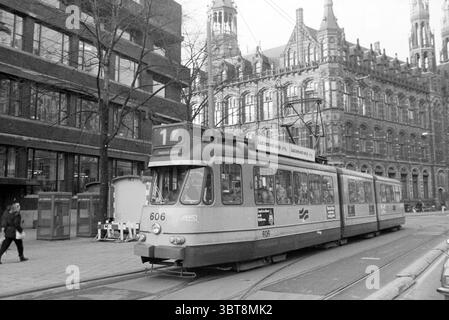 Straßenbahnlinie 1 Amsterdam Tram Amsterdam the Netherlands, Whizgle News, Dutch Desk, Niederlande, 1950 - 2000 am 21-02-1984. Das Bild enthält diese Themen. Die Szene fängt eine historische urbane Umgebung ein, die durch eine Mischung aus architektonischen Stilen gekennzeichnet ist. Vor der Kulisse befindet sich ein markantes Gebäude mit kunstvollen Details, spitzen Türmen, großen Fenstern und komplizierten Ziegelmauern, die an ein Design aus dem späten 19. Jahrhundert erinnern. Die Fassade zeigt eine Vielzahl von Texturen, von glattem Stein bis zu rauem Ziegel, die einen optisch fesselnden Kontrast schaffen. Im Vordergrund eine Straßenbahn, verziert mit einem verblassten Stockfoto