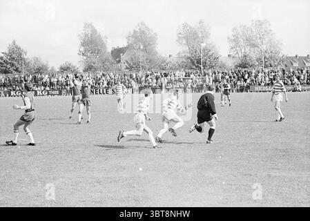 Haarlem - Blauw-Wit Football Haarlem, Whizgle News, Dutch Desk, Niederlande, 1950 - 2000 am 18-05-1969. Diese Themen sind in der Abbildung dargestellt. Die Szene zeigt ein energiegeladenes Fußballspiel, das auf einem gut gepflegten Grasfeld stattfindet. Im Vordergrund sprinten zwei Spieler in leuchtend gestreiften Trikots auf den Schiedsrichter zu, wobei ihre Ausdrücke fokussiert und entschlossen sind. Die Streifen sind überwiegend weiß und grün und stehen in starkem Kontrast zu den dunkleren Tönen des Grases unter den Füßen. Um die Spieler herum ist eine Menge Zuschauer im Hintergrund zu sehen, die sich am Rand des Spielers aufeinanderreiht Stockfoto