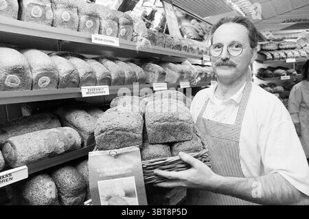 Baker Everts with Bread Santpoort Santpoort, Whizgle News, Dutch Desk, Niederlande, 1950 - 2000 am 06-04-1994. Diese Themen sind in der Abbildung dargestellt. In einer belebten Bäckerei steht ein Mann an der Spitze, der einen Korb mit Brotlaiben hält. Er hat einen dünnen Schnurrbart und trägt eine runde Brille, mit einer Schürze über einem hellen Hemd. Sein Ausdruck vermittelt ein Gefühl von Stolz und Freundlichkeit, während er mit Kunden interagiert oder Brot für den Verkauf zubereitet. Die Kulisse wird von Regalen dominiert, die hoch gestapelt sind mit einer Vielzahl verschiedener Brotsorten, die jeweils sorgfältig angeordnet sind. Stockfoto