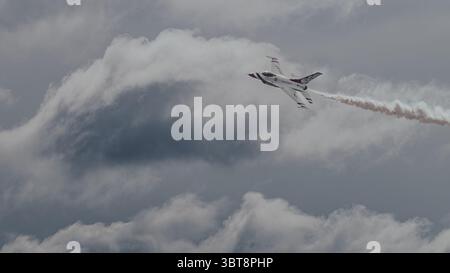 Die USAF Thunderbirds F-16 führt auf der McGuire AFB Airshow am 2025. Mai 2025 einen umgekehrten Aufstieg mit Rauchspur gegen dramatische Wolken durch. Stockfoto