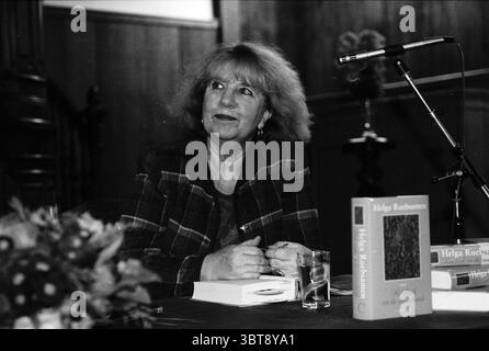 Schriftstellerin Helga Ruebsamen, Whizgle News, Dutch Desk, Niederlande, 1950 - 2000 am 17-11-1997. Das Bild enthält diese Themen. In der Szene sitzt eine Frau mit einer zerzausten, hellen Frisur an einem Tisch und strahlt eine Mischung aus Selbstvertrauen und Nachdenklichkeit aus. Sie trägt eine stilvolle Jacke mit Karomuster in dunklen Grün- und Brauntönen, die ihrem Aussehen einen nostalgischen Touch verleiht. Die Umgebung ist intim, wahrscheinlich ein kleiner Auditorium oder eine Bibliothek, mit Holztäfelung im Hintergrund, die Wärme und Tradition symbolisiert. Der Tisch vor ihr ist ordentlich angeordnet und hält ein paar B Stockfoto