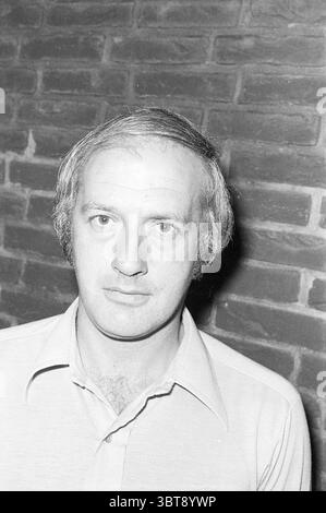 Porträt von Trainer Doorneveld von NAS Halfweg Football People and Trainer, Whizgle News, Dutch Desk, Niederlande, 1950 - 2000 auf 30-08-1976. Diese Themen werden in der Abbildung angezeigt. Die Szene zeigt einen Mann mit neutralem Ausdruck, der vor einer strukturierten Ziegelwand positioniert ist. Er hat ein kurzes, helles Haar, das einige subtile Anzeichen von Ausdünnung zeigt. Sein Hemd ist leicht und mit Kragen versehen, was zu einem einfachen, aber klassischen Aussehen beiträgt. Der Hintergrund besteht aus dunklen, abgenutzten Ziegeln, die einen Erdton erzeugen, der sich von der Kleidung des Mannes abhebt. Die Beleuchtung ist weich und gleichmäßig, und das Gesicht wird leicht beleuchtet Stockfoto