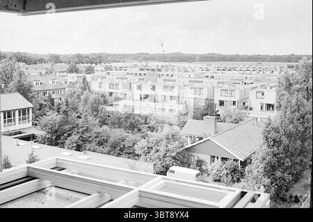 Neubau Häuser in allen Arten von Formen., Whizgle News, Dutch Desk, Niederlande, 1950 - 2000 am 18-07-1973. Das Bild enthält diese Themen. Die Szene zeigt eine weitläufige Wohngegend von oben aus, die eine Anordnung von Häusern und Grünflächen zeigt. Die Gebäude sind überwiegend modern im Design, mit flachen Dächern und rechteckigen Formen, mit einer Mischung aus hellen und dunklen Farbtönen, die einen einheitlichen architektonischen Stil suggerieren. Der Vordergrund bietet einen Blick auf Dächer, von denen einige mit Schindeln und andere mit kontrastierenden Materialien dekoriert sind, während entlang ein Baugerüst zu sehen ist Stockfoto
