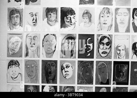 Kunstwerk in Meat Hall, Whizgle News, Dutch Desk, Niederlande, 1950 - 2000 am 12-11-1992. Das Bild enthält diese Themen. Die Szene zeigt ein Raster mit verschiedenen Porträts, die an einer Wand angezeigt werden. Jedes Porträt ist einzigartig und zeigt eine breite Palette von Gesichtsausdrücken, von heiter bis intensiv, und fängt ein Spektrum von Emotionen ein. Das Kunstwerk ist überwiegend in Schwarzweiß gehalten, wobei Schwarz-, weiß- und Grautöne verwendet werden, was der Gesamtkomposition eine starke und dramatische Qualität verleiht. Die Gesichter unterscheiden sich im Stil, von abstrakten Interpretationen bis hin zu realistischeren Darstellungen, und alle haben eine einzigartige Leistung Stockfoto